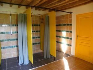 a bathroom with yellow and gray shower stalls at Chambres d'hôtes Les cabris in Verneix