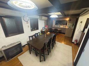 a dining room with a table and chairs and a kitchen at ゲストハウス あめりか和 in Namerikawa