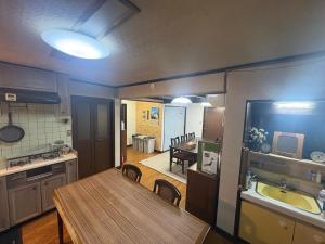 a kitchen and dining room with a wooden table in a kitchen at ゲストハウス あめりか和 in Namerikawa
