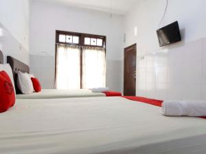 two beds in a room with a tv on the wall at RedDoorz @ Seturan Raya in Yogyakarta
