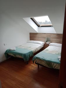 two beds in a room with a window at Pension Ameneiral in O Pedrouzo