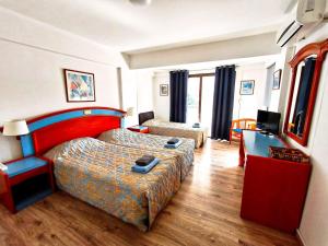 a hotel room with a bed and a television at Petalmo City Apartments in Larnaca