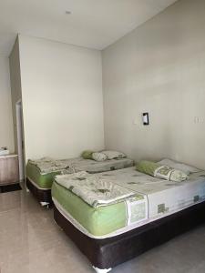two twin beds in a room with a wall at Uciek Tengger Hotel Bromo in Ngadisari
