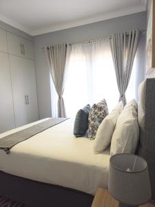 a bedroom with a large white bed with a window at Belo Villa Clarens in Clarens