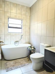 a bathroom with a tub and a toilet and a window at Belo Villa Clarens in Clarens +29 photos