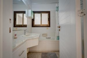 a white bathroom with a sink and a tub at Aphrodite Limassol Apartment in Limassol +76 photos
