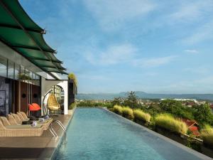 a swimming pool on the side of a house at The Manohara Hotel Yogyakarta in Yogyakarta
