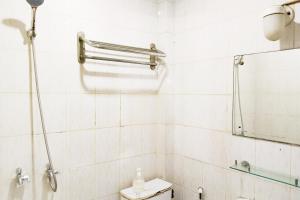 a white tiled bathroom with a shower and a toilet at NamRoom at Margot Jaksa in Jakarta +22 photos