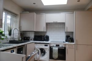 a kitchen with white cabinets and a washing machine at Airy 3 bedroom House in Norwood