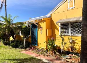 a yellow house with a blue door at The Mango Shack in Carnarvon