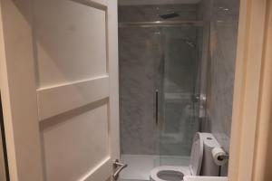 a bathroom with a toilet and a glass shower at Airy 3 bedroom House in Norwood