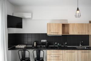 a kitchen with black tiled walls and wooden cabinets at K Studios in Faliraki