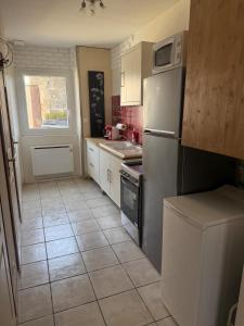 a kitchen with a white refrigerator and a tile floor at Studio Cardinal in Renage