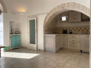 a kitchen with an arched doorway and an archway at Trullidea in Alberobello +43 photos