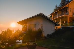 a house with the sunset in the background at Chill Berg Resort - Bodimettu in Theni