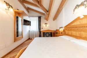 a bedroom with a large bed and a desk at Family Hotel La Perla in Fiera di Primiero
