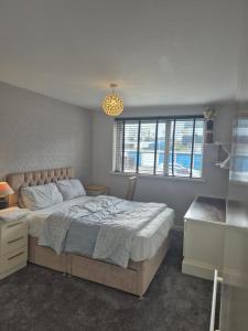 a bedroom with a large bed and a window at Three bedroom house with a garden in Redhill