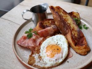 a plate of breakfast food with eggs bacon and toast at Nui. HOSTEL & BAR LOUNGE in Tokyo