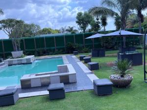 a swimming pool with chairs and an umbrella at Africa Prestige Boutique Hotel in Benoni