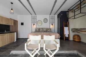 a bedroom with a bed and two white chairs at K Studios in Faliraki +8 photos