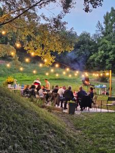 Eine Gruppe von Menschen sitzt nachts an Tischen in einem Park. in der Unterkunft PianPieve Family Apartments vicino Assisi in Assisi