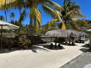 a beach with palm trees and benches and umbrellas at Korail Bleu in Rodrigues Island