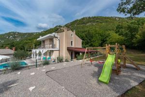 a playground with a slide in front of a house at Kika's Home in Križišće