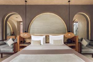 a bedroom with a large bed and two chairs at Astera Villa Seminyak by Ini Vie Hospitality in Seminyak