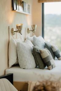a bunch of pillows sitting on a bed with a window at KOOLNA pod kopcem in Valašské Meziříčí