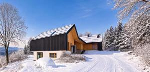 a house is covered in snow with a dirt road at Haus am FELS, Alpenaster in Hermagor
