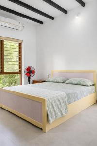 a bedroom with a large bed in a white room at MAK Mansion in Kotikulam