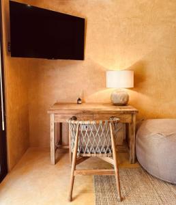 a wooden table with a chair and a television on a wall at Sunset at Las Cabanas in El Nido