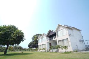 a white building with a tree in front of it at Riviera Resort and Hotel in Durg