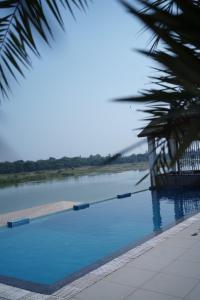 a swimming pool next to a body of water at Riviera Resort and Hotel in Durg