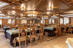 a dining room with tables and chairs and a chandelier at Family Hotel La Perla in Fiera di Primiero
