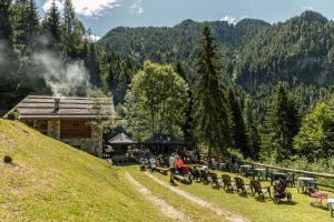 a group of people sitting on a hill near a cabin at Family Hotel La Perla in Fiera di Primiero