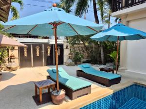 a pool with chairs and umbrellas next to a swimming pool at Sibaja Palms Sunset Beach Luxury Villa in Taling Ngam Beach