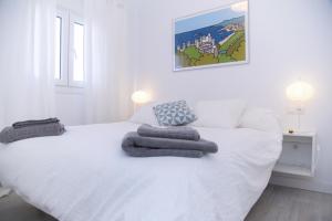 Un dormitorio con una cama blanca con toallas. en Casa Picasso 6, en Málaga