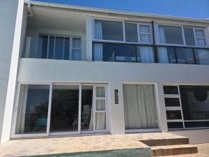 a white building with sliding doors and windows at Hartsepunt Seesig in Hartenbos +25 photos