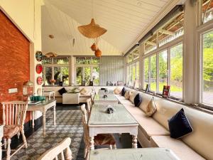 a large room with a couch and tables and windows at The Rising Sun Farm Karjat - Luxury Stays - Couple Friendly in Karjat