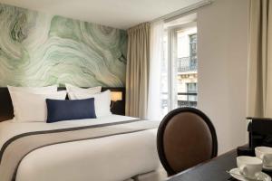 a bedroom with a large bed and a table with chairs at Queen Mary Opera in Paris