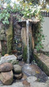 a waterfall in front of a stone wall with rocks at Country Homes Srilanka in Mount Lavinia