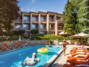 ein Hotel mit einem Schwimmbad, in dem Schwäne schwimmen in der Unterkunft Hotel Villa Pax in Balatonalmádi