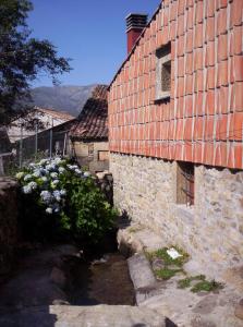 an old brick building with flowers in front of it at El Tormal in Navalonguilla