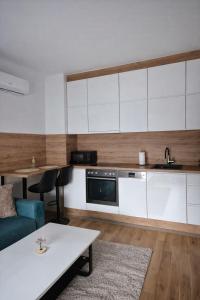 a kitchen with white cabinets and a table at Una Apartmani Musique in Tuzla