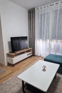 a living room with a tv and a white table at Una Apartmani Musique in Tuzla