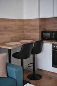 a kitchen with a table and two chairs and a microwave at Una Apartmani Musique in Tuzla