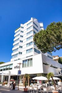 a large white building with tables and chairs at Hotel Cristallo in Riccione