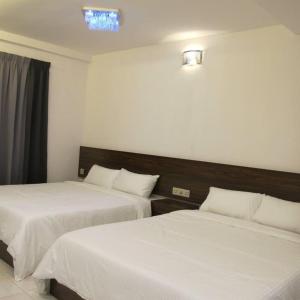 a hotel room with two beds with white sheets at Pangkor Lot 10 Moonlight in Kampong Sungai Udang