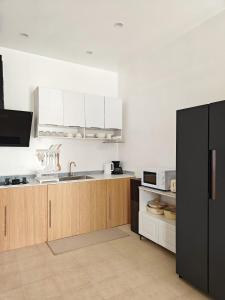 a kitchen with white cabinets and a black refrigerator at The Shores House-Royal Plams Tres by THE HOUSE in Dauis